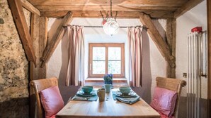 A rustic dining area with a wooden table, checkered cushions, and a hanging light fixture. - Apartment HANS - Schusterhäusl (Samerberg)
