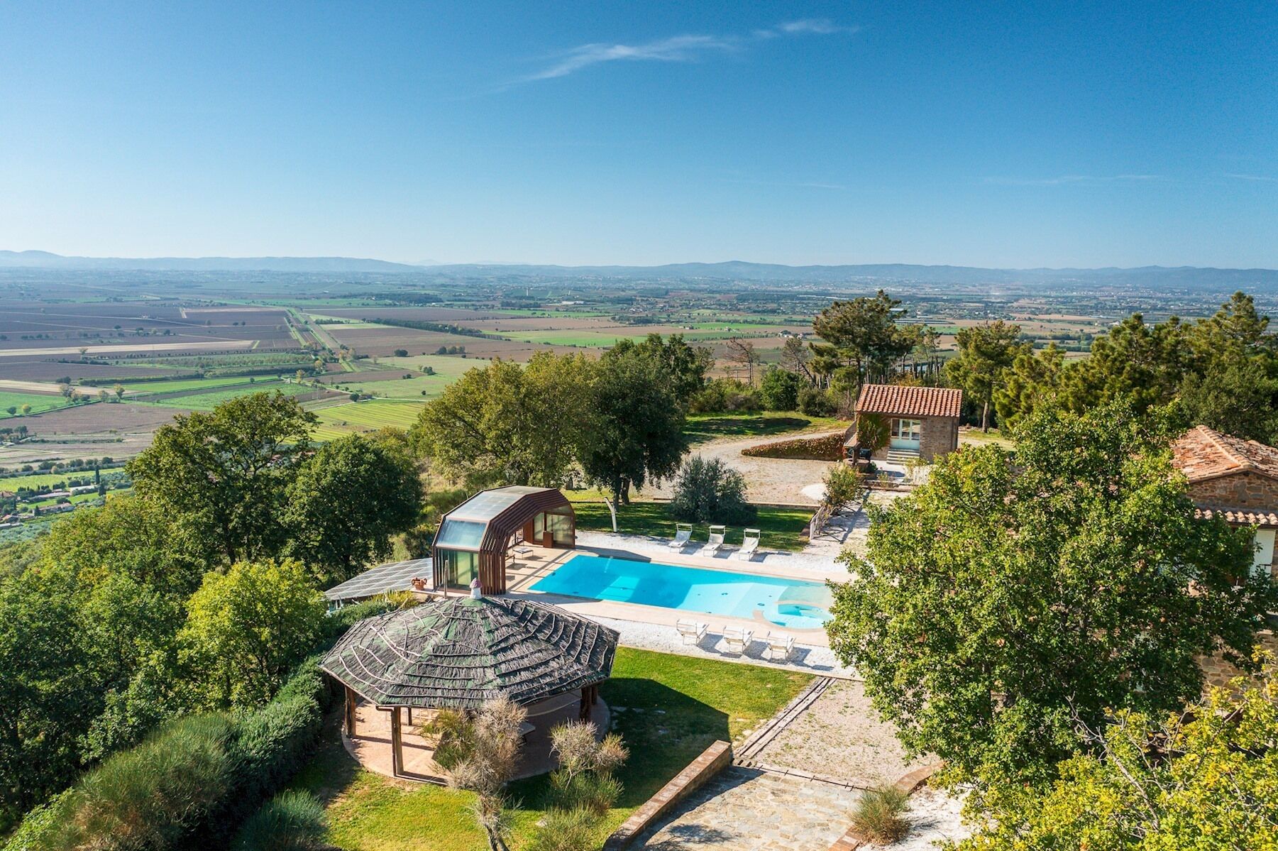 Una villa con piscina, una pequeña casa de huéspedes y un pabellón.