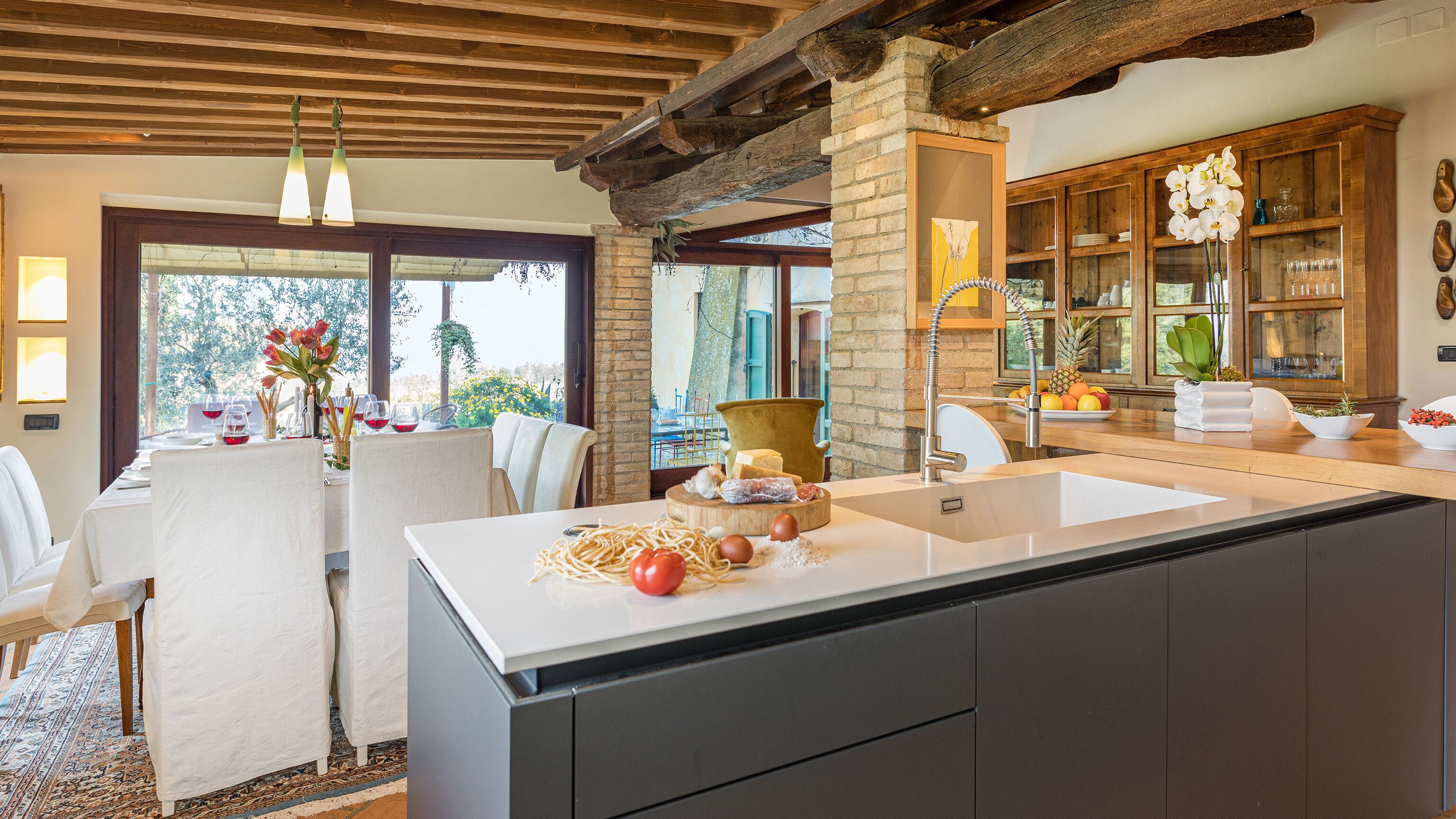 Cozinha moderna com uma ilha grande, vigas de madeira e vista para o exterior.