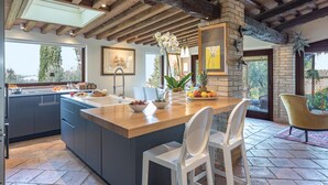 A modern kitchen with a large island, dark cabinetry, and a view of the outdoors. - Casale Santa Lucia 8+2, Emma Villas (Bettona)