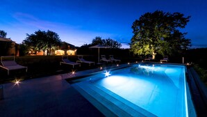 A swimming pool with lounge chairs and a covered area, surrounded by trees and buildings. - La Casa nei Vigneti 10, Emma Villas (Catignano)