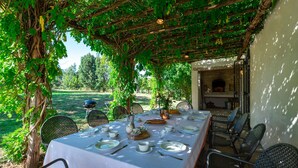 An outdoor dining area with a table set for four, surrounded by chairs, under a vine-covered pergola. - La Casa nei Vigneti 10, Emma Villas (Catignano)