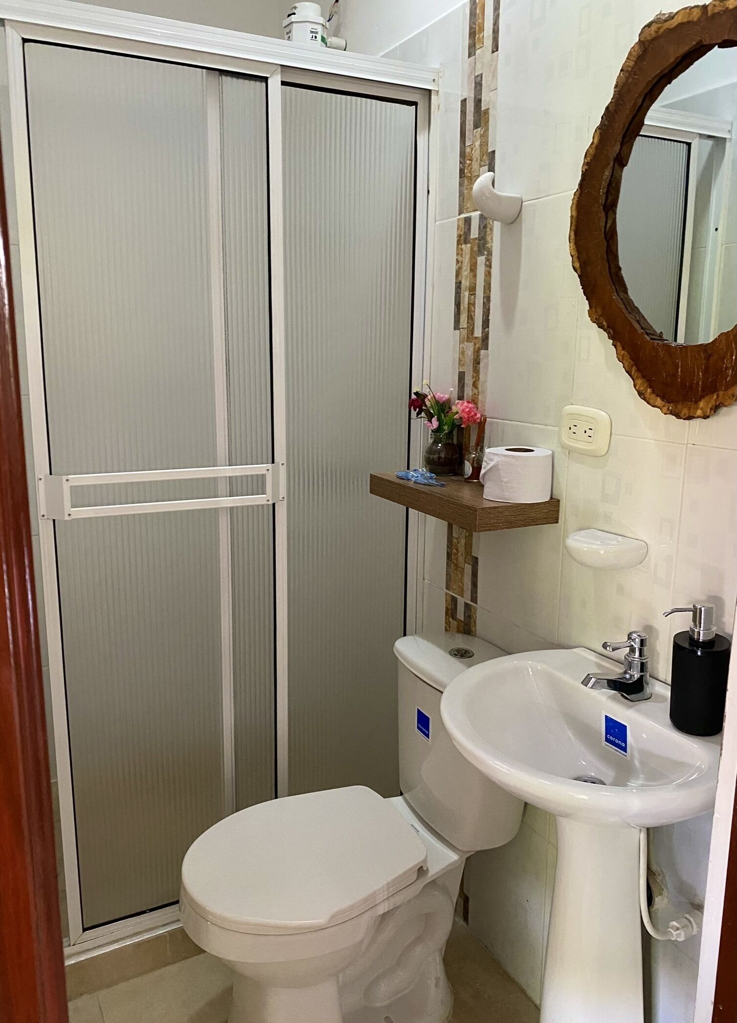 A bathroom with a toilet, sink, and shower enclosure.