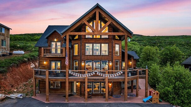Un gran albergue de madera de varios pisos con un balcón y una pequeña zona de juegos.
