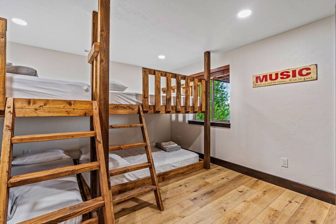 Une chambre avec un lit superposé en bois, une échelle et un panneau mural sur lequel est écrit « MUSIQUE ».