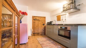 Eine kleine Küche mit Holzboden, einem rosa Kühlschrank und Edelstahlgeräten.