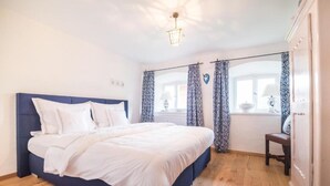 Ein Schlafzimmer mit einem großen Bett, Holzboden und einem Fenster mit Vorhängen.