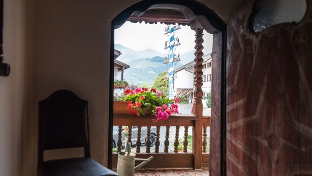Ein Holzbalkon mit Blick auf einen Berg und traditionelle Gebäude.