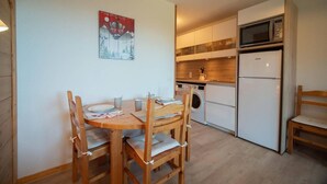 A compact kitchen with a microwave, oven, and washing machine. There is a dining table with chairs and a painting on the wall. - 5m from ski slopes, 4th floor, view mountain, balcony, ski locker, 25m², Valmorel (Valmorel)