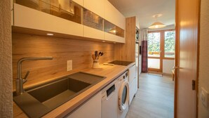 A modern kitchen with a built-in washing machine, wooden countertops, and a large window. - 5m from ski slopes, 4th floor, view mountain, balcony, ski locker, 25m², Valmorel (Valmorel)