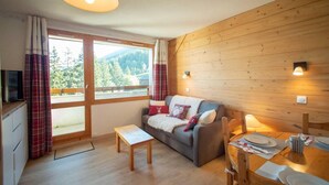 A cozy room with a wooden interior, a sofa, a small table, and a dining area with a table and chairs. - 5m from ski slopes, 4th floor, view mountain, balcony, ski locker, 25m², Valmorel (Valmorel)