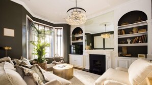 A living room with a fireplace, a chandelier, and a bookshelf.