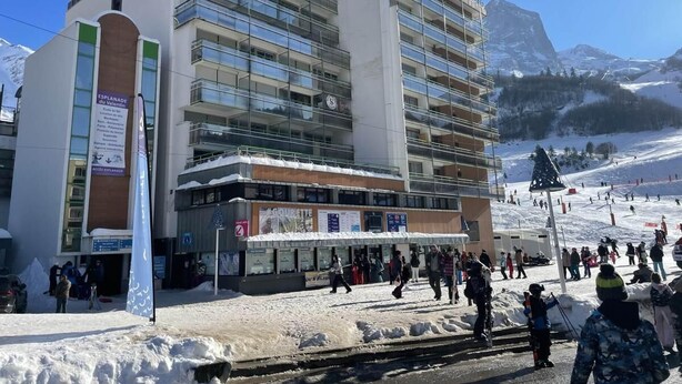 Un hotel de varios pisos con un centro de esquí al fondo.