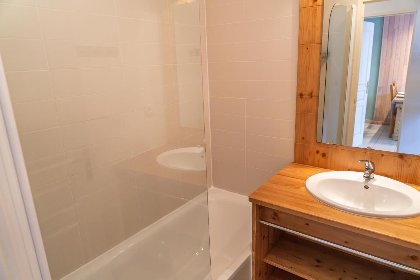 A bathroom with a glass-enclosed shower, a wooden vanity with a sink, and a mirror.