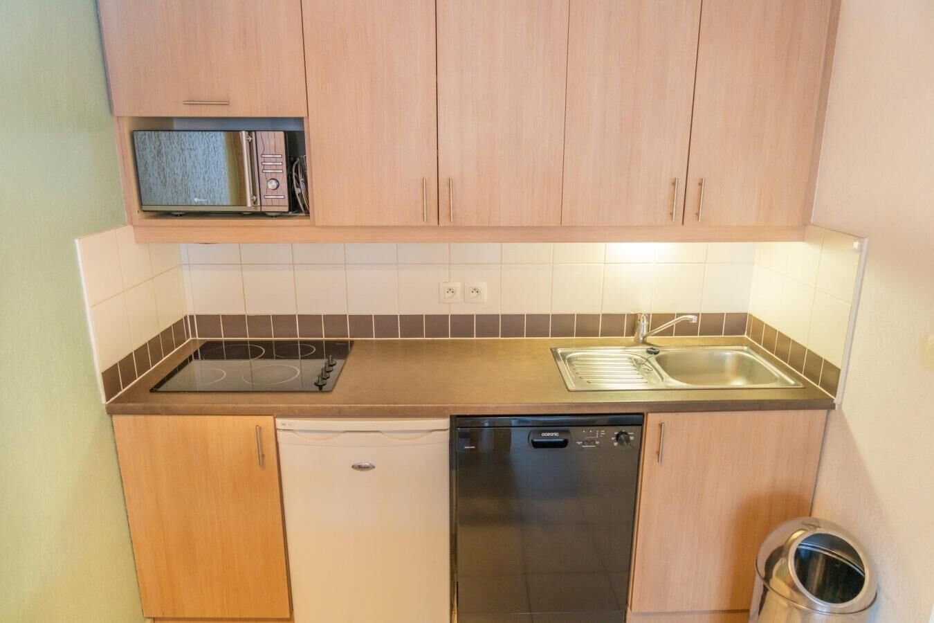 A compact kitchen with a dishwasher, a stove, and a sink.