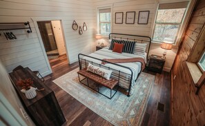 Un dormitorio acogedor con cama, banqueta, mesitas de noche y ventana con vistas.