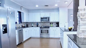 A modern kitchen with white cabinets, stainless steel appliances, and a wooden floor. - The Hidden Gem - Huge Floor Plan - Game Room (Sulphur)