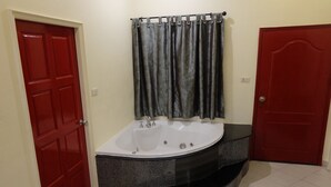 A bathroom with a freestanding bathtub, a red door, and a shower curtain.