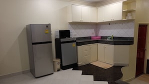 A compact kitchen with white cabinets, a refrigerator, a microwave, and a sink.