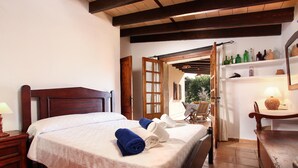 A bedroom with a wooden bed, white linens, a wooden nightstand, and a small table with a lamp. - FONTXICA (JUANITO ). Nice and cosy villa (Puerto Pollensa)