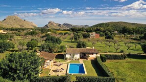 A villa with a swimming pool, surrounded by lush greenery and mountains in the background. - FONTXICA (JUANITO ). Nice and cosy villa (Puerto Pollensa)
