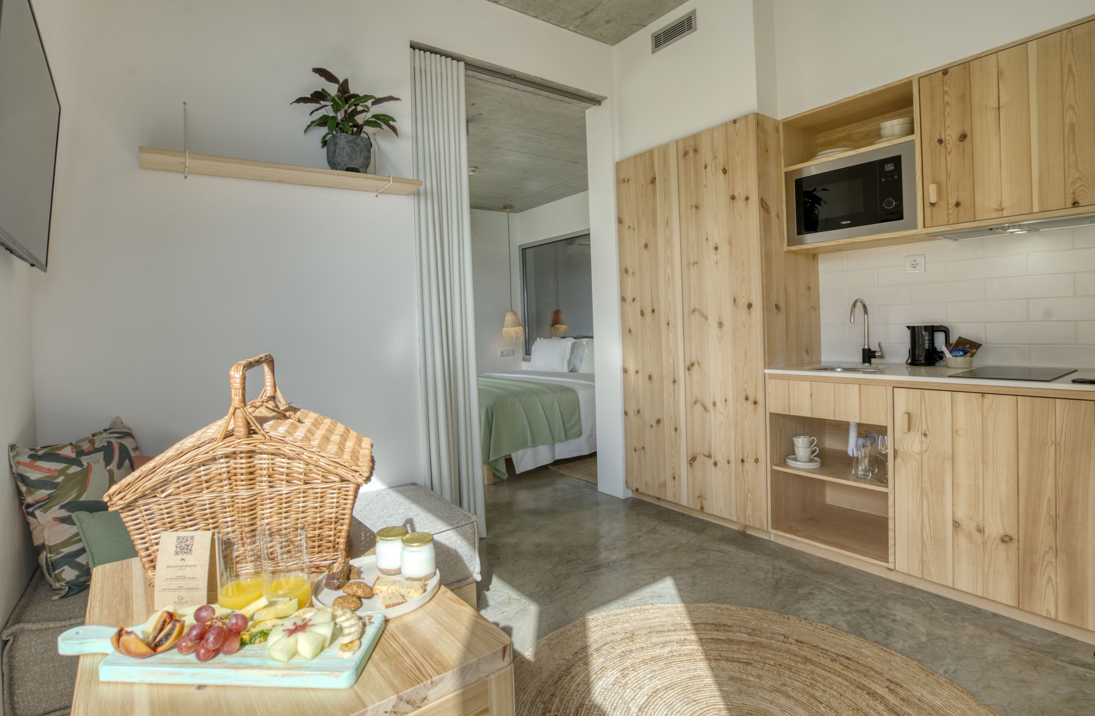 A modern kitchen with wooden cabinets, a microwave, and a breakfast setup on the counter.