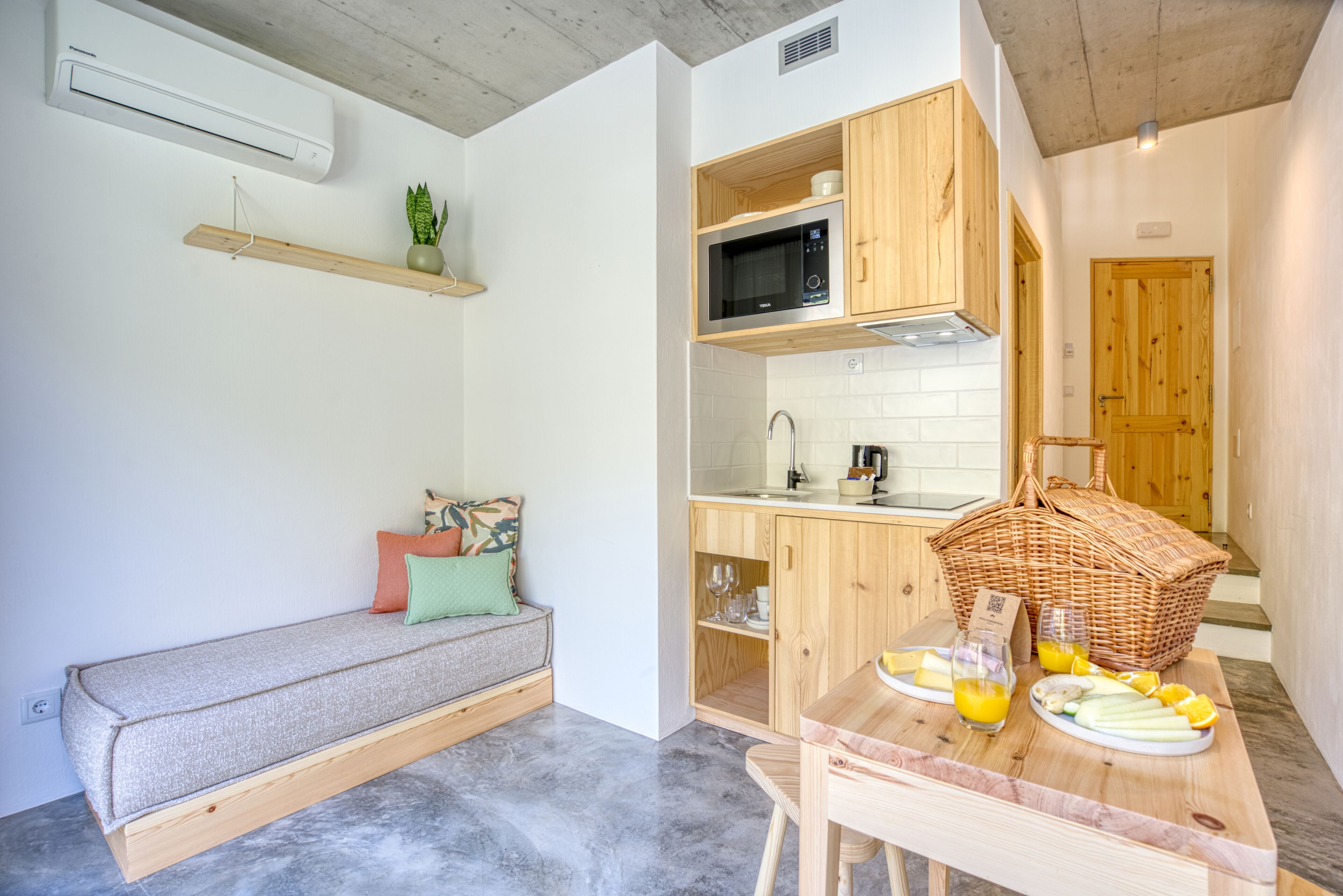 A compact kitchen with wooden cabinets, a microwave, and a dining area with a table set for breakfast.