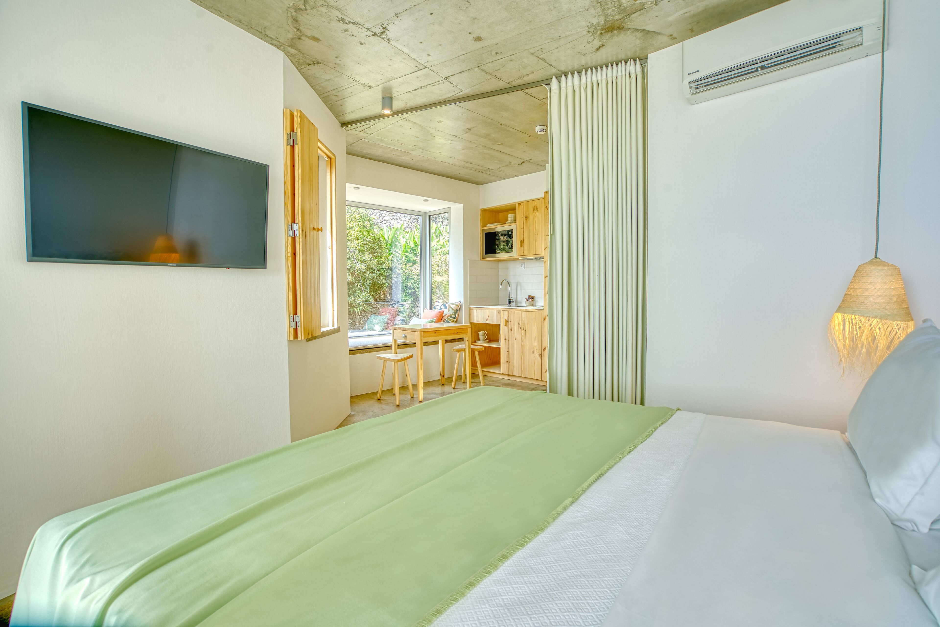 A bedroom with a bed, a desk, and a window.