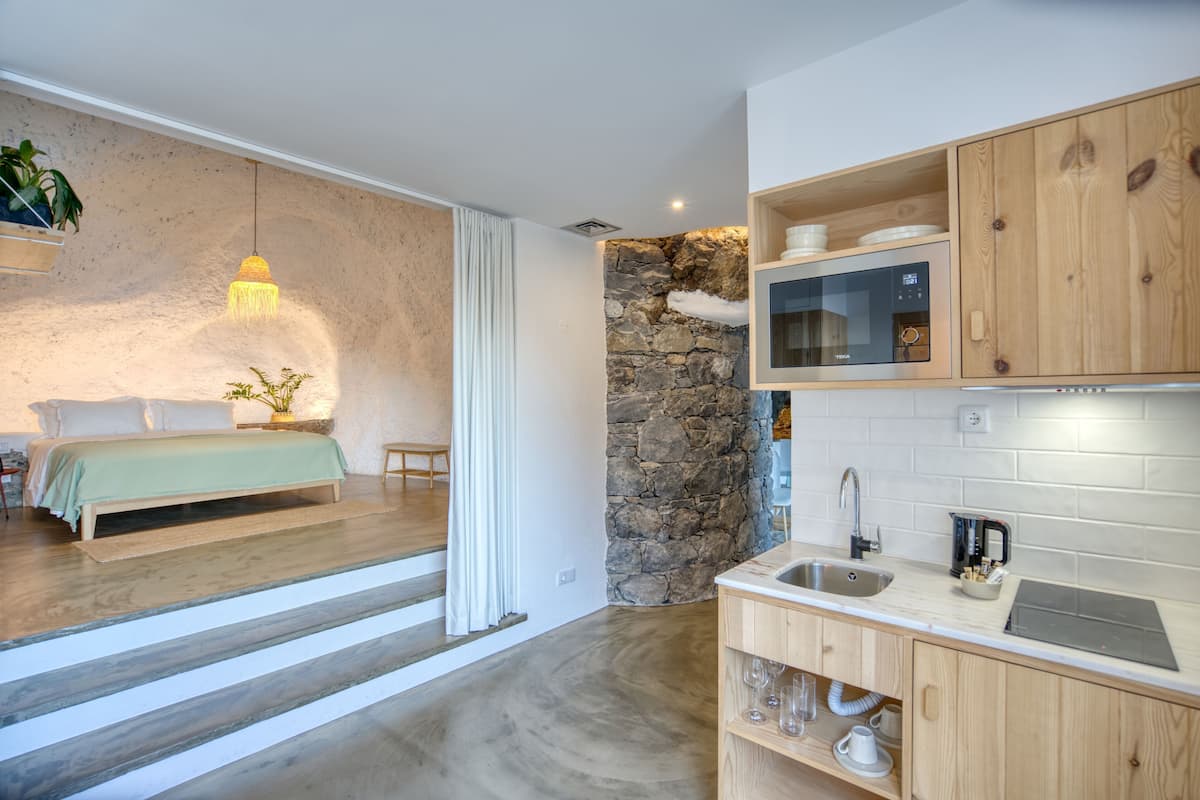 Uma cozinha moderna com parede decorada em pedra, armários de madeira e micro-ondas embutido.
