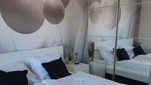 A modern bedroom with a large bed, a bedside table, a mirror, and abstract wall art. - D&B staycation Ferienpark (Niedenstein)
