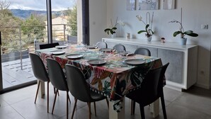 A modern dining area with a large table set for six, surrounded by chairs. - Quiet modern villa with swimming pool (Le Tignet)