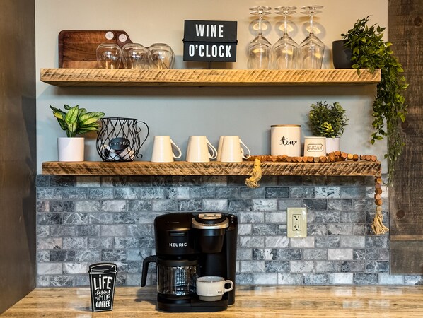 A kitchen with a coffee maker, a sign reading "WINE O'CLOCK", and various kitchen items on shelves. - *New* Modern Cabin w/ Serene Forest Views/Hot Tub/Spacious Decks (Blue Ridge)