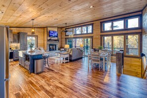 A spacious cabin interior with a kitchen, dining area, and living room, featuring wooden floors and large windows. - *New* Modern Cabin w/ Serene Forest Views/Hot Tub/Spacious Decks (Blue Ridge)
