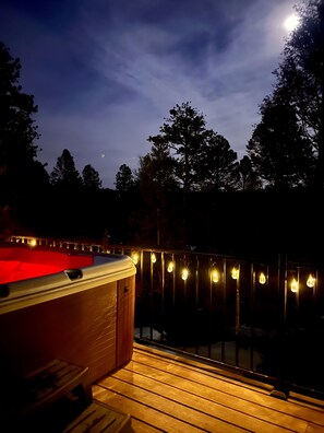 A hot tub on a wooden deck with string lights, surrounded by trees and a night sky. - Secluded Stargazing Mountain Retreat, Hot Tub, Big Kitchen, Fireplace, Arcade (Florissant)
