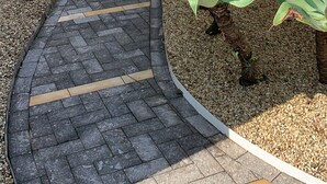 Un chemin menant à un bâtiment doté d’un toit recouvert de tuiles et de murs blancs.