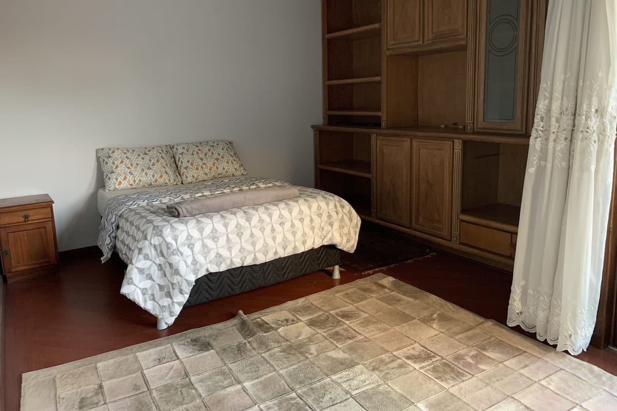Un dormitorio con cama, armario de madera y alfombra.
