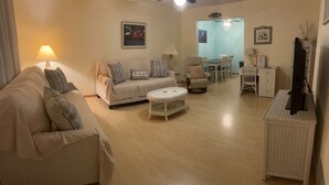 Una sala de estar con sofá, sillón, mesa de centro y comedor con sillas y una mesa.