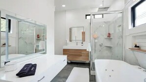 Une salle de bain moderne avec deux lavabos, une douche à l’italienne en verre et un grand miroir.