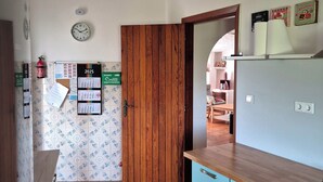 Une cuisine avec une porte en bois, une horloge et un calendrier accroché au mur.
