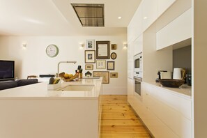 Uma cozinha moderna com ilha central, piso de madeira e forno embutido.
