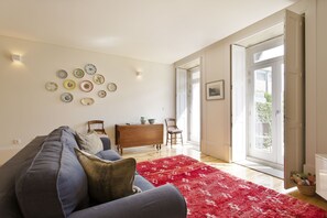 Uma sala de estar com um sofá, um tapete vermelho, um armário de madeira e uma parede decorada com pratos.