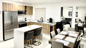 Eine moderne Küche mit Kühlschrank, Mikrowelle und Herd. Ein Essbereich mit Tisch und Stühlen vorhanden.