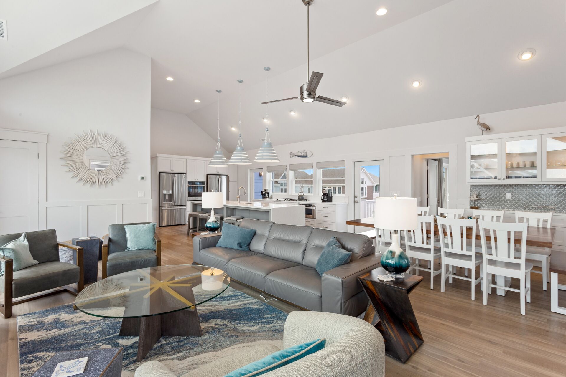 A spacious living area with a modern kitchen, a dining area, and a ceiling fan.