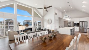 Een ruime keuken met moderne apparatuur, een eethoek met een grote houten tafel en uitzicht op omliggende huizen.
