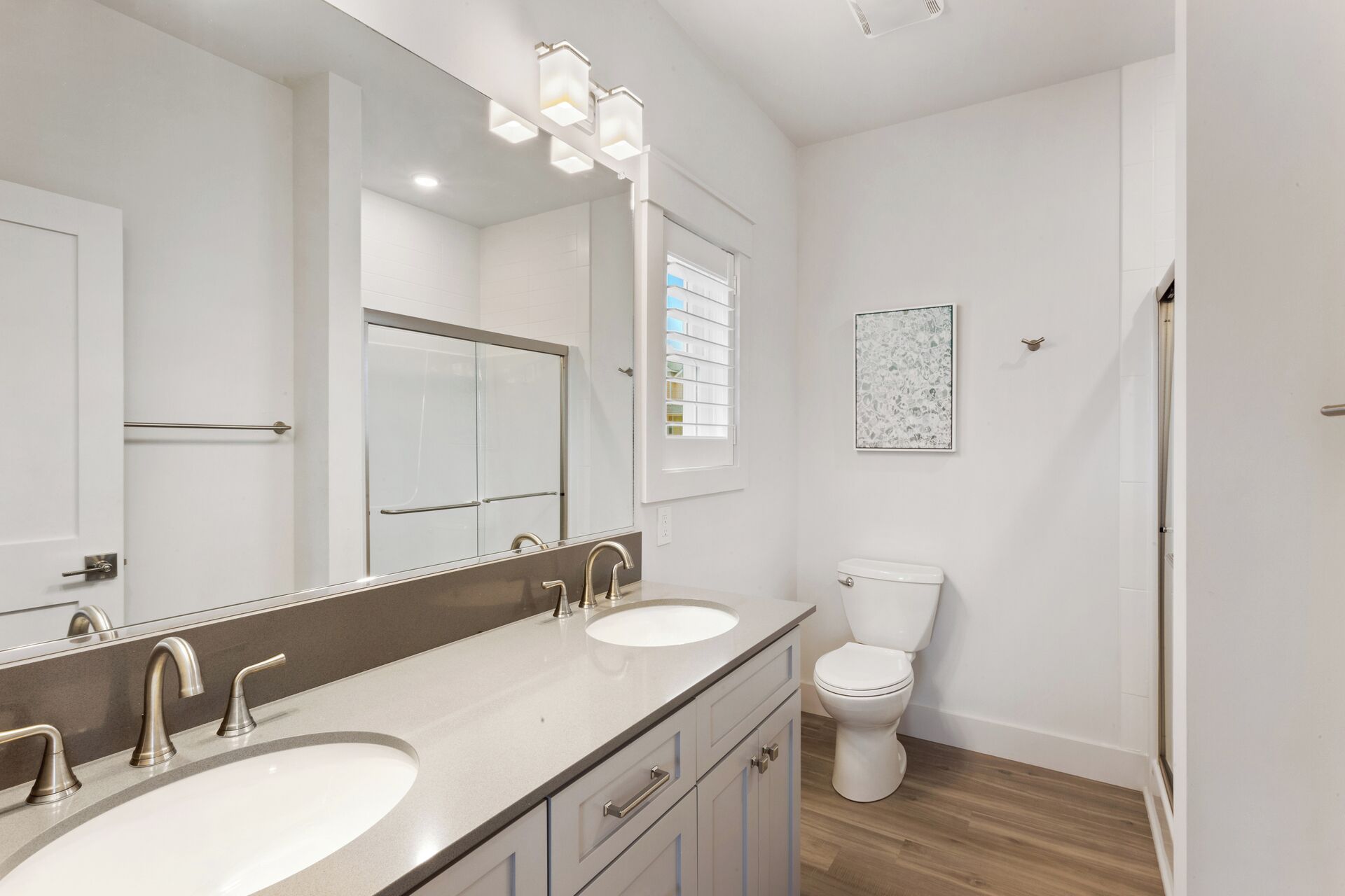 Een moderne badkamer met twee wastafels, een toilet en een grote spiegel.