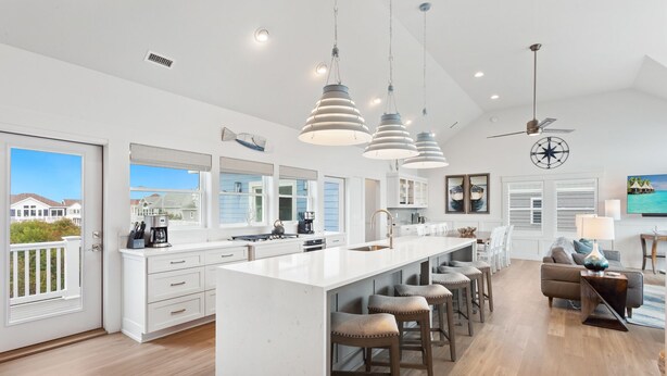 Een moderne keuken met een groot eiland, hanglampen en uitzicht op zee.