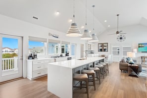 Eine moderne Küche mit einer großen Kochinsel, Pendelleuchten und Meerblick.