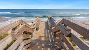 Een houten looppad dat naar een strand leidt, met uitzicht op de oceaan.