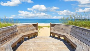 A wooden boardwalk leading to a beach with a clear view of the ocean and sky. - Seaside Oasis *Oceanfront Luxury w/ PRIVATE Beach Walkway, Pool, Elevator, Media Rm, Pool Table... (Nags Head)