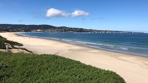 A beach with a clear view of the ocean, a sandy shore, and a distant town.